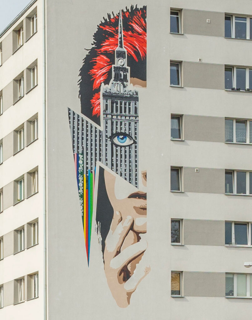 Mural na ścianie bloku, przedstawiający Davida Bowie patrzącego przez Pałac Kultury i Nauki.
