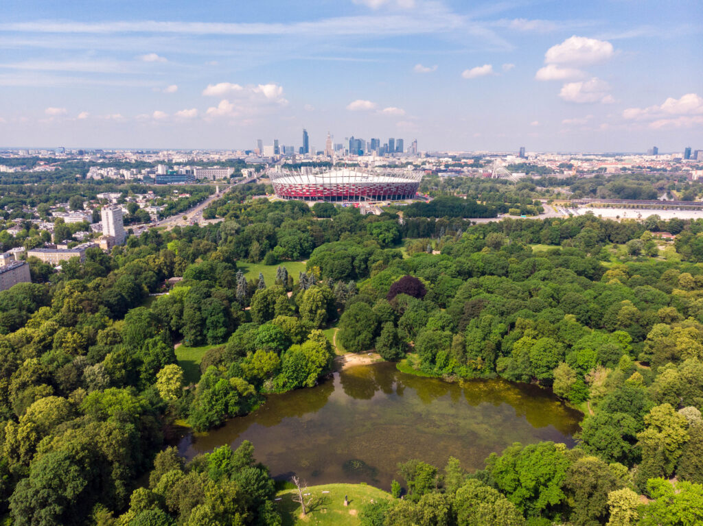 Widok z drona na zieleń parku Skaryszewskiego, w tle Stadion Narodowy i centrum Warszawy.