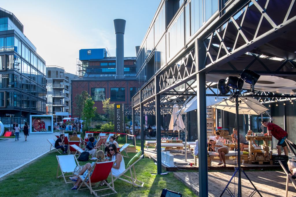 Elektrownia Powiśle, ludzie odpoczywają w ogródkach restauracyjnych, inni spacerują, dzień, lato.