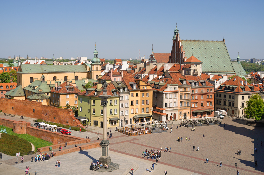 Widok na Stare Miasto z dzwonnicy przy kościele św. Anny, Kolumna Zygmunta III Wazy, kamienice i kościoły, mury obronne, ogródki restauracyjne, spacerują ludzie, dzień, lato.